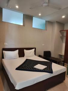 a bedroom with a bed with white sheets and two windows at Hotel Green Land in Mohali +1 photo