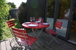 une table rouge avec des chaises et des verres à vin sur une terrasse dans l'établissement Green Tiny Village Harz - Tiny House Nature 19, à Osterode