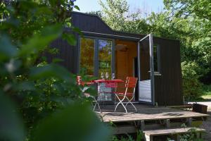une petite maison avec une table et des chaises sur une terrasse dans l'établissement Green Tiny Village Harz - Tiny House Nature 19, à Osterode