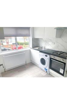 a kitchen with a stove and a washer and dryer at Sunny Gardens 3-Bed Apartment in London in Hendon +4 photos