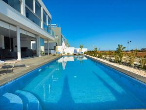 ein großer blauer Swimmingpool vor einem Gebäude in der Unterkunft Villa Manta Chrysos - Brand New Luxury 3 Bedroom Protaras Villa in Protaras