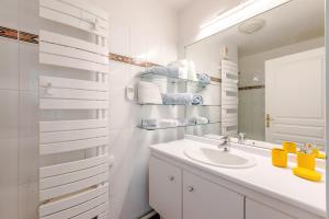 a white bathroom with a sink and a mirror at Appartement Cosy in Paris +26 photos