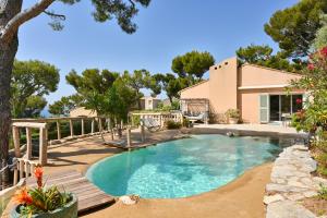 a swimming pool with a wooden deck and a house at villa les nefliers vue panoramique mer et plage à pied in Cassis