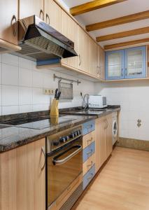 a kitchen with wooden cabinets and a stove top oven at Apartamentos Campanas de San Juan in Santiago de Compostela