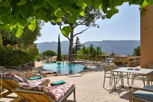 a patio with chairs and a table and a pool at villa les nefliers vue panoramique mer et plage à pied in Cassis