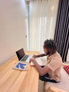 a man sitting at a table with a laptop computer at Live Well Rwanda House in Kigali