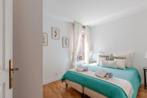 a white bedroom with a large bed with green sheets at Appartement Cosy in Paris