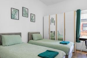 zwei Betten in einem Zimmer mit Spiegel in der Unterkunft Newly renovated 3 Ensuite bedroom house in bury, 5 people in Bury