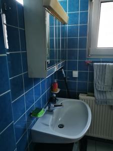 a blue tiled bathroom with a sink and a mirror at Ferienwohnung Zimmer in Darmstadt