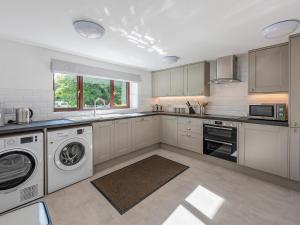 Una cocina con gabinetes blancos y lavadora y secadora. en The Farmhouse, en Hawes