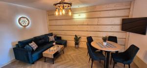 a living room with a couch and a table and chairs at Apartamenty Wiktorówka in Poronin