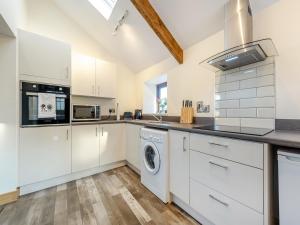 a kitchen with white cabinets and a washer and dryer at Ty Gwair - Uk41512 in Llanfair Clydogau +13 photos