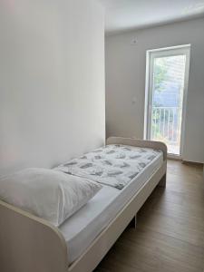 un lit dans une chambre blanche avec une fenêtre dans l'établissement True Apartment Jure - FREE Boat Trip for 7 or more Nights!, à Biograd na Moru