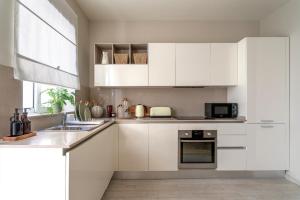 a white kitchen with white cabinets and a sink at Chic and modern apartment with yard LDEM1-2 in Sliema