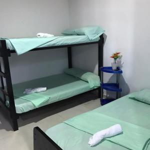 2 literas en una habitación con sábanas verdes en Hotel y cabañas dyd, en Bazán