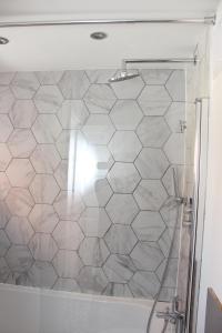 a shower with a white tiled wall in a bathroom at King-size 3Bed House in Leicester in Leicester