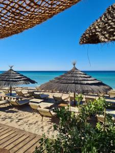 a beach with chairs and umbrellas and the ocean at Le Onde di Rossella in Torre Lapillo