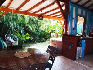 a wooden table and chairs on a patio with a porch at Blue Kaz Caraïb in Pointe-Noire