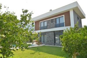 a house with a green yard in front of it at Villa Opera Kemer Müstakil Villa in Kemer