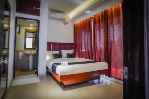 a bedroom with a bed with red curtains and a sink at Needs Bay Watch in Cox's Bazar