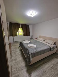 a bedroom with a large bed with two towels on it at Apartament LUKE in Tîrgu Ocna