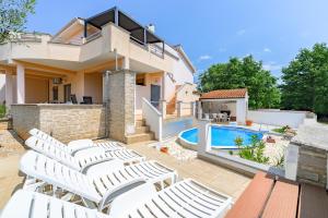 a villa with a swimming pool and white chairs at House Monique in Rošini