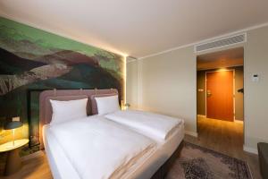 - un grand lit blanc dans une chambre avec un tableau dans l'établissement The Rilano Hotel München, à Munich