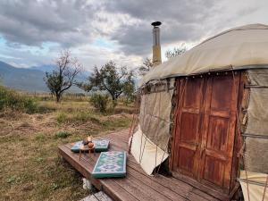 a yurt with a wooden deck with a table in front at Family Eco Farm Getaway in Ryskulovo