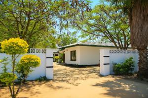 una casa con una valla blanca y árboles en Virgo Hostels, en Gaborone