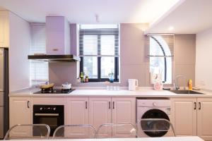 una cucina con armadi bianchi, lavandino e finestre di ZHome-Three floors 4 bedrooms - near Nanjing Road a Shanghai