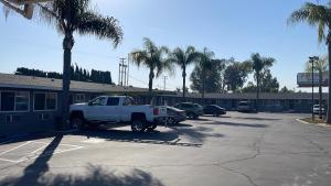 un camión blanco estacionado en un estacionamiento con palmeras en King's Inn Motel, en Kingsburg 2 fotos más