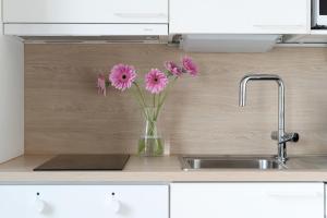 a vase filled with pink flowers sitting next to a sink at Sonetti - Metso library apartments Come in! in Tampere +37 photos