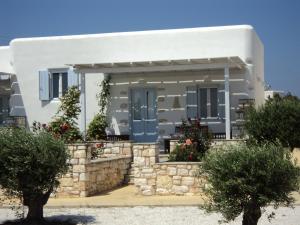 a white house with blue doors and a stone wall at Ambelas Mare Apartments in Ambelas
