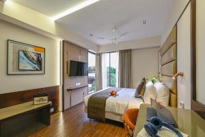 a hotel room with a bed and a desk with a laptop at Hotel Grand Girdhar Premier in Indore