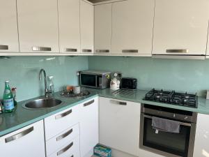 a kitchen with white cabinets and a sink and a microwave at 2 Bed Ap Covent Garden in London