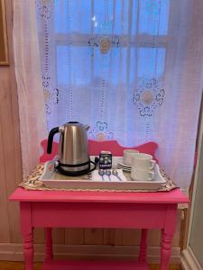 ein rosa Tisch mit einem Teekessel und Tassen darauf in der Unterkunft La Forillonne in Gaspé