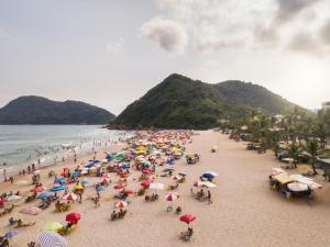 a group of people on a beach with umbrellas at Tombo Beach in Guarujá +95 photos