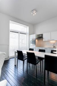 a white kitchen with a dining table and chairs at Point du jour in Ostend
