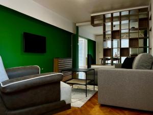 - un salon avec des murs verts, un canapé et des chaises dans l'établissement Modern Flat in Prishtina Centre, à Pristina