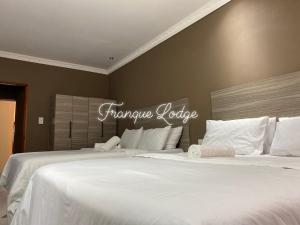 Dos camas blancas en un dormitorio con un cartel en la pared. en Franque Lodge, en Durban