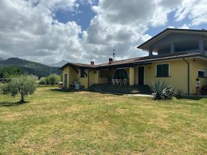 a small yellow house with a grass yard at La Paulonia Country House in Capezzano Pianore,