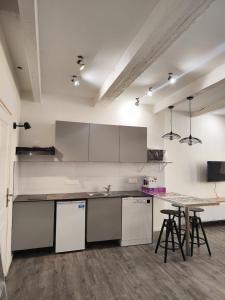 a kitchen with white cabinets and a table with stools at Aix Centre-ville in Aix-en-Provence