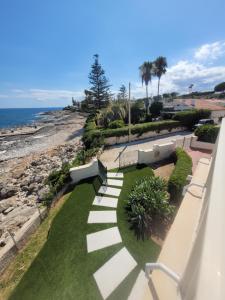 a walkway with benches and a view of the ocean at Villa Stella in Fontane Bianche