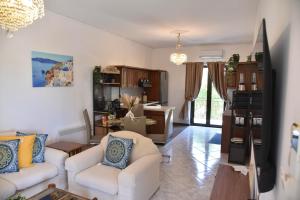a living room with two white chairs and a kitchen at Aegean Escape in Nea Makri