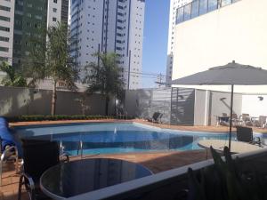 a swimming pool with a table and an umbrella at Imprensa III · Comfort and family in Brasilia in Brasilia +68 photos