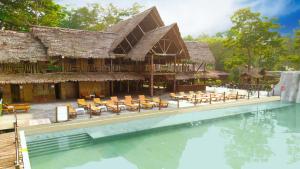 莱蒂西亚Hotel Amazon by On Vacation的有游泳池和桌椅的度假村