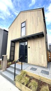 Un edificio de madera con una puerta negra y escaleras. en Vibrant Frankton Villa, en Queenstown