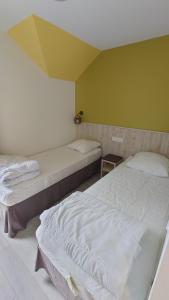 zwei Betten stehen in einem Zimmer mit einer gelben Wand in der Unterkunft Charmant cottage dans Village Normandy Garden, Pierre & Vacances in Branville