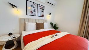 Your Home in Bucharest - Premium 1BR Apartments in ONE Cotroceni في بوخارست: غرفة نوم بسرير احمر وبيض وطاولة