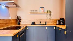 Your Home in Bucharest - Premium 1BR Apartments in ONE Cotroceni في بوخارست: مطبخ مع دواليب زرقاء وقمة كونتر